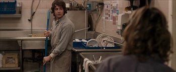 Movie still from “Snow Angels” (2007), directed by David Gordon Green – A man standing next to a sink in a kitchen; Medium shot, Over the shoulder angle