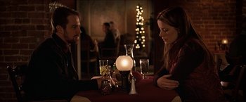 Movie still from “Snow Angels” (2007), directed by David Gordon Green – A man and a woman sitting at a dinner table; Medium shot, Over the shoulder angle