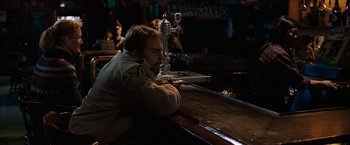 Movie still from “Snow Angels” (2007), directed by David Gordon Green – A man sitting at a bar with his head resting on his arm; Medium shot, Over the shoulder angle