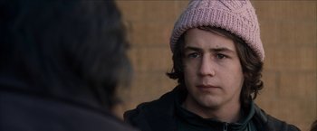 Movie still from “Snow Angels” (2007), directed by David Gordon Green – A young man wearing a pink hat looking at the camera; Close Up shot, Over the shoulder angle