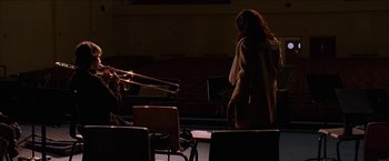 Movie still from “Snow Angels” (2007), directed by David Gordon Green – A woman standing next to a man playing a trombone; Extreme Wide shot, Over the shoulder angle