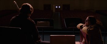 Movie still from “Snow Angels” (2007), directed by David Gordon Green – A person sitting in a room with a chair in front of them; Wide shot, Over the shoulder angle