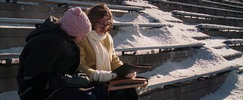 Movie still from “Snow Angels” (2007), directed by David Gordon Green – Two people sitting on a bench looking at a book; Medium shot, High angle