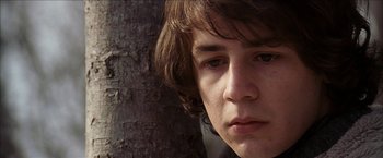 Movie still from “Snow Angels” (2007), directed by David Gordon Green – A person with a tree in the background; Close Up shot, Low angle