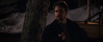 Movie still from “Snow Angels” (2007), directed by David Gordon Green – A man standing next to a tree in the dark; Close Up shot, Over the shoulder angle
