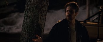 Movie still from “Snow Angels” (2007), directed by David Gordon Green – A man standing next to a tree in the dark; Close Up shot, Over the shoulder angle