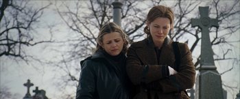 Movie still from “Snow Angels” (2007), directed by David Gordon Green – Two women standing next to each other near a tree; Medium shot, Low angle
