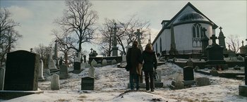 Movie still from “Snow Angels” (2007), directed by David Gordon Green – Two people standing in front of a grave yard; Wide shot, Over the shoulder angle