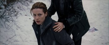 Movie still from “Snow Angels” (2007), directed by David Gordon Green – A woman in a black jacket and a man in a black suit; Medium shot, Low angle