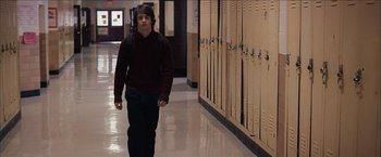 Movie still from “Snow Angels” (2007), directed by David Gordon Green – A man walking down a hallway in front of lockers; Wide shot, Over the shoulder angle