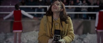 Movie still from “Snow Angels” (2007), directed by David Gordon Green – A woman holding an old fashioned camera in front of an audience; Medium shot, Low angle