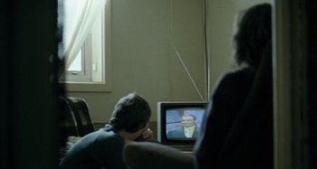 Movie still from “The Snowtown Murders” (2011), directed by Justin Kurzel – Two people sitting in front of a television; Medium shot, Over the shoulder angle