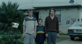 Movie still from “The Snowtown Murders” (2011), directed by Justin Kurzel – Three young men standing in front of a house; Wide shot, Low angle