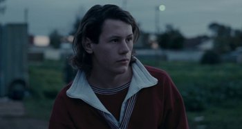 Movie still from “The Snowtown Murders” (2011), directed by Justin Kurzel – A man with long hair and a red jacket; Close Up shot, Over the shoulder angle
