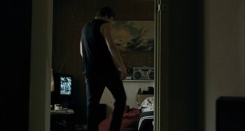 Movie still from “The Snowtown Murders” (2011), directed by Justin Kurzel – A man standing in a living room holding a wii controller; Wide shot, Low angle
