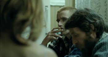 Movie still from “The Snowtown Murders” (2011), directed by Justin Kurzel – A man smoking a cigarette in front of two other people; Close Up shot, Over the shoulder angle