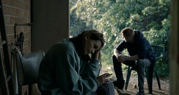 Movie still from “The Snowtown Murders” (2011), directed by Justin Kurzel – A man and a woman sitting on a bench looking at a cell phone; Medium shot, Over the shoulder angle