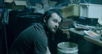 Movie still from “The Snowtown Murders” (2011), directed by Justin Kurzel – A man sitting in front of a trash can in a room; Close Up shot, Low angle