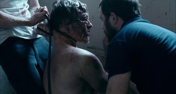 Movie still from “The Snowtown Murders” (2011), directed by Justin Kurzel – A man is being held by another man in a room; Close Up shot, Over the shoulder angle