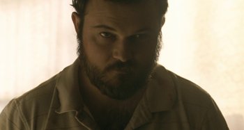 Movie still from “The Snowtown Murders” (2011), directed by Justin Kurzel – A man with a goatee and a beard stares at the camera; Close Up shot, Low angle