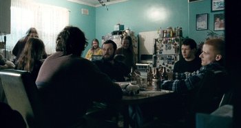 Movie still from “The Snowtown Murders” (2011), directed by Justin Kurzel – A group of people sitting around a table in a room; Medium shot, Over the shoulder angle