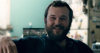 Movie still from “The Snowtown Murders” (2011), directed by Justin Kurzel – A person with a beard smiling; Close Up shot, Over the shoulder angle