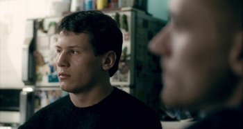 Movie still from “The Snowtown Murders” (2011), directed by Justin Kurzel – A man in a black t - shirt is looking into the distance; Close Up shot, Over the shoulder angle