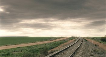 Movie still from “The Snowtown Murders” (2011), directed by Justin Kurzel – A car driving down the middle of the road on a cloudy day; Extreme Wide shot, High angle