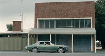 Movie still from “The Snowtown Murders” (2011), directed by Justin Kurzel – An older car parked in front of a building; Extreme Wide shot, Low angle