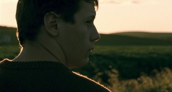 Movie still from “The Snowtown Murders” (2011), directed by Justin Kurzel – A young man looking into the distance in a field; Close Up shot, Low angle