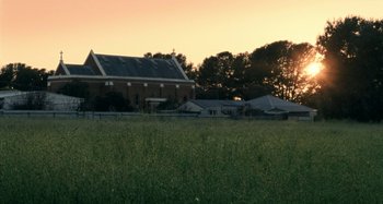 Movie still from “The Snowtown Murders” (2011), directed by Justin Kurzel – A field of grass with a building in the background; Extreme Wide shot, Low angle