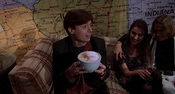 Movie still from “So I Married an Axe Murderer” (1993), directed by Thomas Schlamme – A man sitting on top of a couch holding a bowl of food; Medium shot, High angle