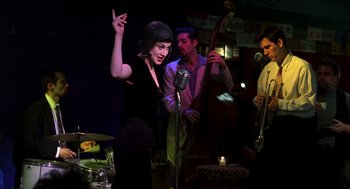 Movie still from “So I Married an Axe Murderer” (1993), directed by Thomas Schlamme – A group of people that are performing on a stage; Medium shot, Over the shoulder angle