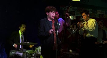 Movie still from “So I Married an Axe Murderer” (1993), directed by Thomas Schlamme – A man in a suit and tie is singing; Medium shot, Low angle