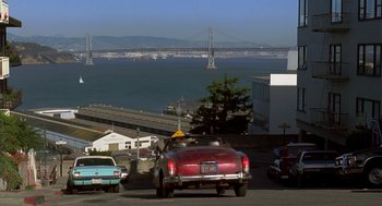 Movie still from “So I Married an Axe Murderer” (1993), directed by Thomas Schlamme – A red car driving down a street next to the ocean; Extreme Wide shot, High angle