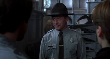 Movie still from “So I Married an Axe Murderer” (1993), directed by Thomas Schlamme – A man wearing a hat and a uniform is smiling; Close Up shot, Over the shoulder angle