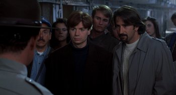 Movie still from “So I Married an Axe Murderer” (1993), directed by Thomas Schlamme – A group of men standing next to each other in the dark; Close Up shot, Over the shoulder angle