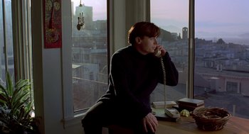 Movie still from “So I Married an Axe Murderer” (1993), directed by Thomas Schlamme – A man sitting in front of a window on a phone; Medium shot, High angle