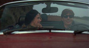 Movie still from “So I Married an Axe Murderer” (1993), directed by Thomas Schlamme – A man and a woman sitting in the back seat of a red car; Medium shot, Over the shoulder angle