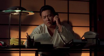 Movie still from “So I Married an Axe Murderer” (1993), directed by Thomas Schlamme – A man sitting at a desk talking on a phone; Close Up shot, Low angle