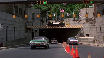 Movie still from “Something Wild” (1986), directed by Jonathan Demme – Cars are driving down the street under an overpass; Wide shot, High angle