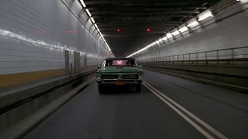 Movie still from “Something Wild” (1986), directed by Jonathan Demme – A car driving down a road in a tunnel; Wide shot, Low angle