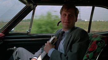 Movie still from “Something Wild” (1986), directed by Jonathan Demme – A man sitting in the driver's seat of a car; Medium shot, Low angle