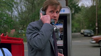 Movie still from “Something Wild” (1986), directed by Jonathan Demme – A man talking on a payphone while wearing a suit and tie; Close Up shot, Low angle
