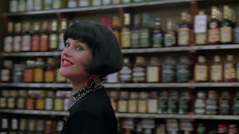 Movie still from “Something Wild” (1986), directed by Jonathan Demme – A woman in a black dress is standing in front of shelves; Close Up shot, Low angle