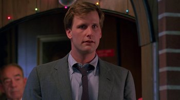 Movie still from “Something Wild” (1986), directed by Jonathan Demme – A man wearing a suit and tie standing in front of a building; Close Up shot, Low angle