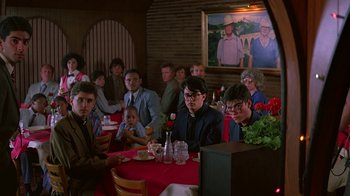 Movie still from “Something Wild” (1986), directed by Jonathan Demme – A group of people sitting at a table with food; Medium shot, Over the shoulder angle