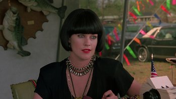Movie still from “Something Wild” (1986), directed by Jonathan Demme – A woman with black hair wearing a black top and red lipstick; Close Up shot, Over the shoulder angle