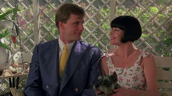 Movie still from “Something Wild” (1986), directed by Jonathan Demme – A man and a woman holding a small dog; Medium shot, Low angle