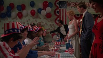 Movie still from “Something Wild” (1986), directed by Jonathan Demme – A group of people sitting at a table wearing patriotic hats; Wide shot, High angle